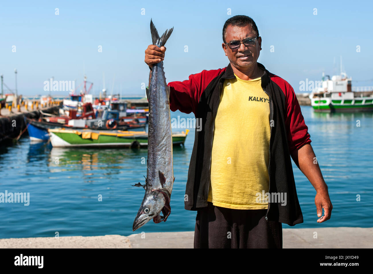 Fisherman fadiel savah con un pesce in harbor Kalk Bay, Città del Capo. Foto Stock