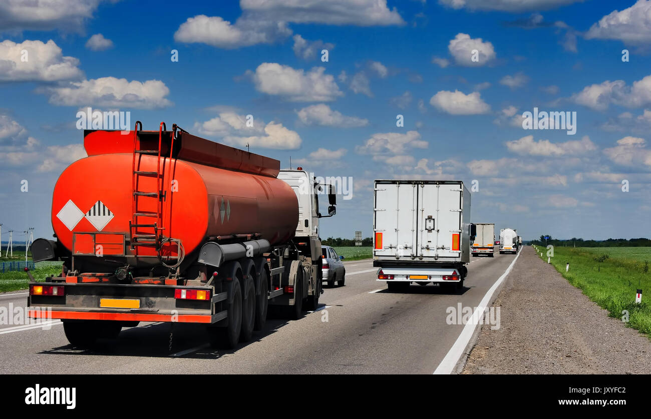 Un'autostrada con camion, camion cisterna. Contro lo sfondo del blu cielo molto nuvoloso Foto Stock