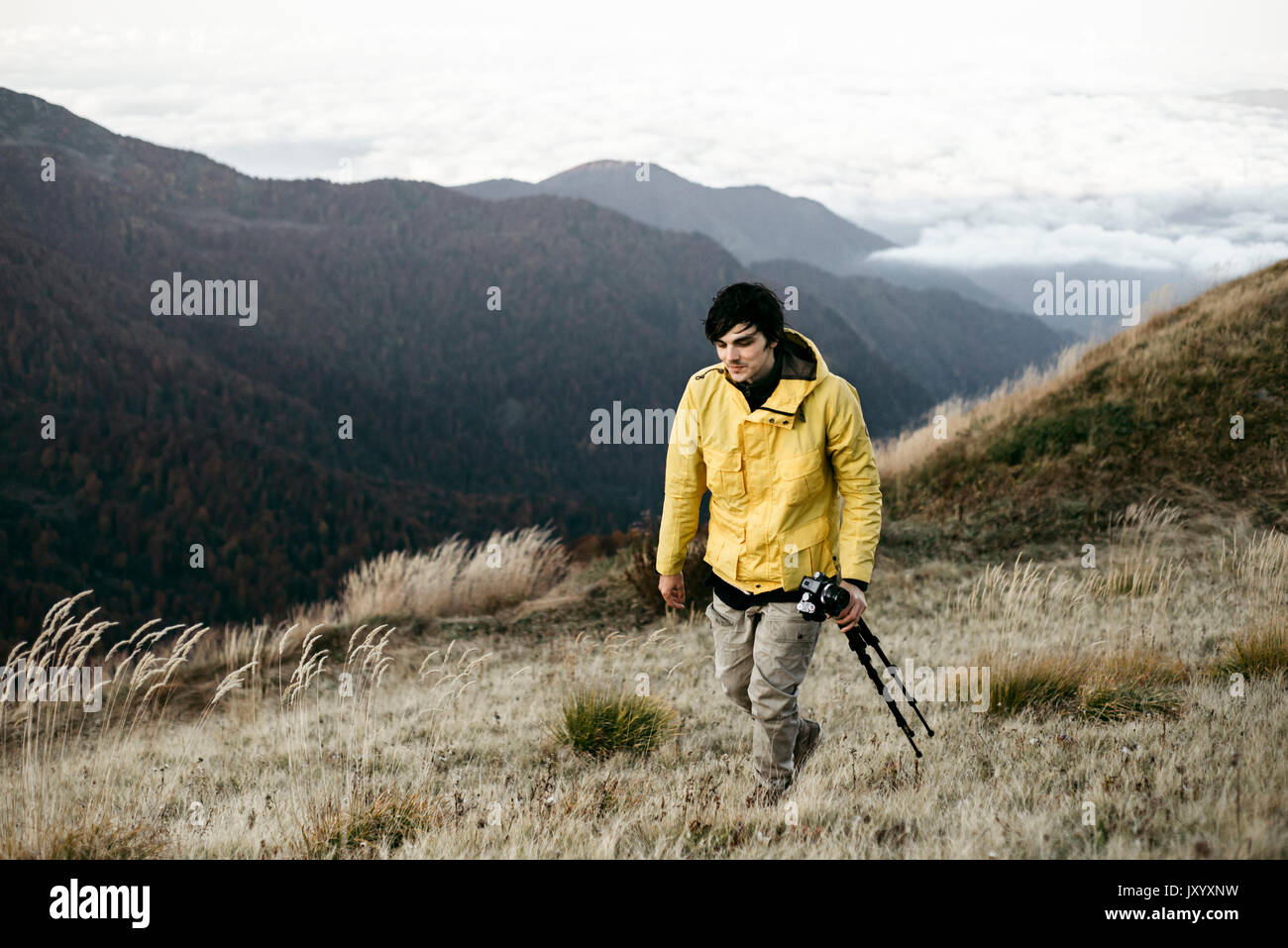 Uomo caucasico che trasportano il treppiede in remoto paesaggio di montagna Foto Stock