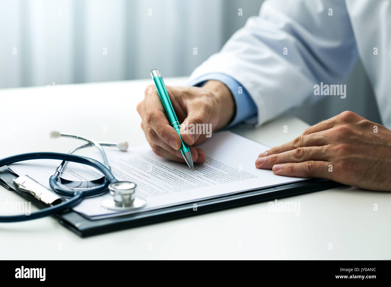 Medico la scrittura di documenti alla scrivania in ufficio cliniche Foto Stock