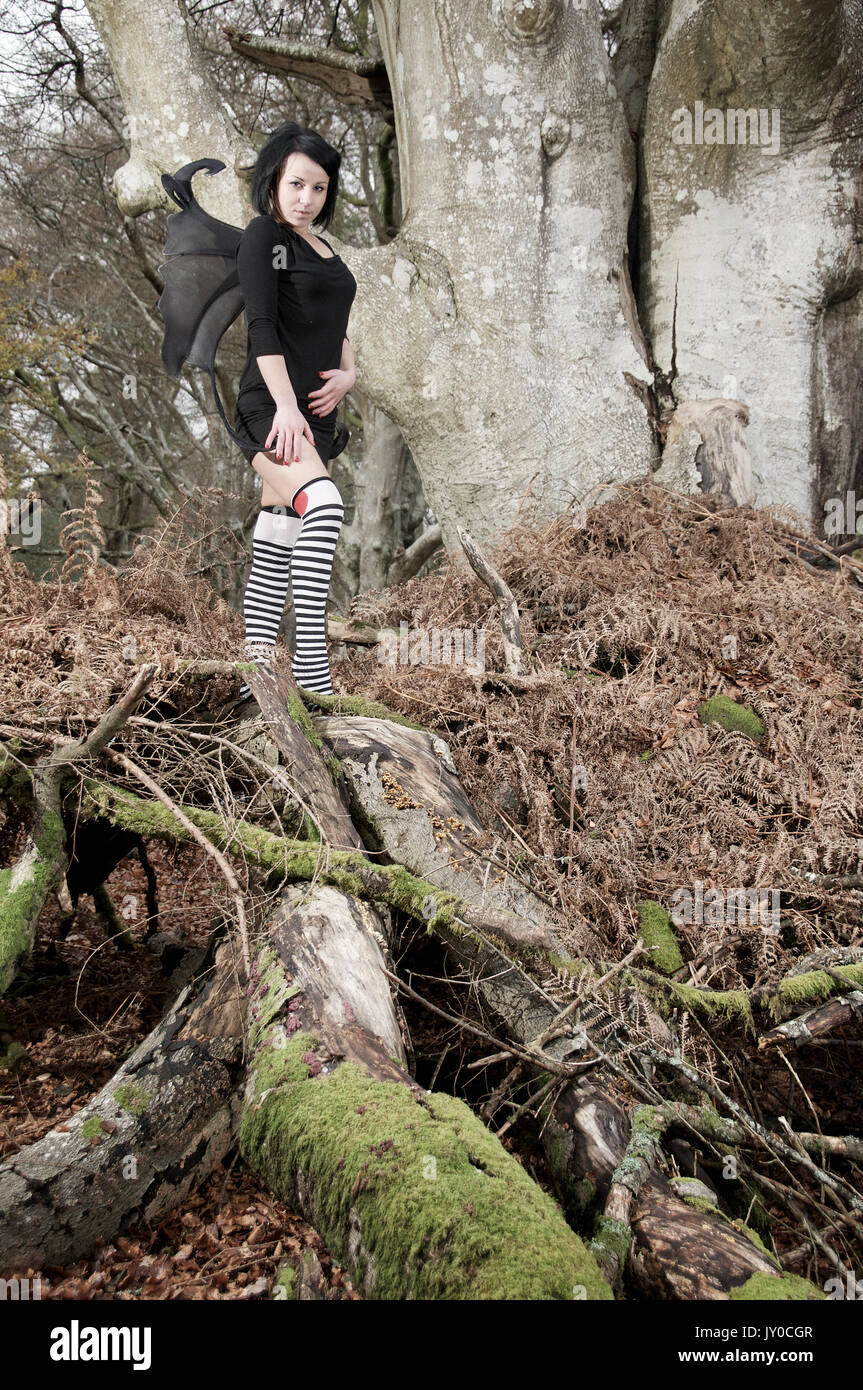 Bella ragazza in un percorso di foresta che indossa un abito nero con le ali Foto Stock
