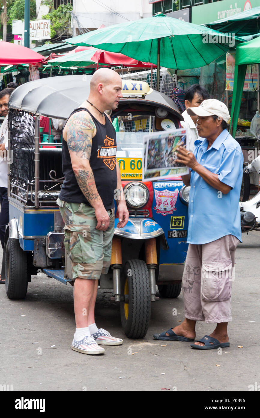 Tourist negoziando con tuk tuk driver per un giro, Khao San Road, Bangkok, Thailandia Foto Stock