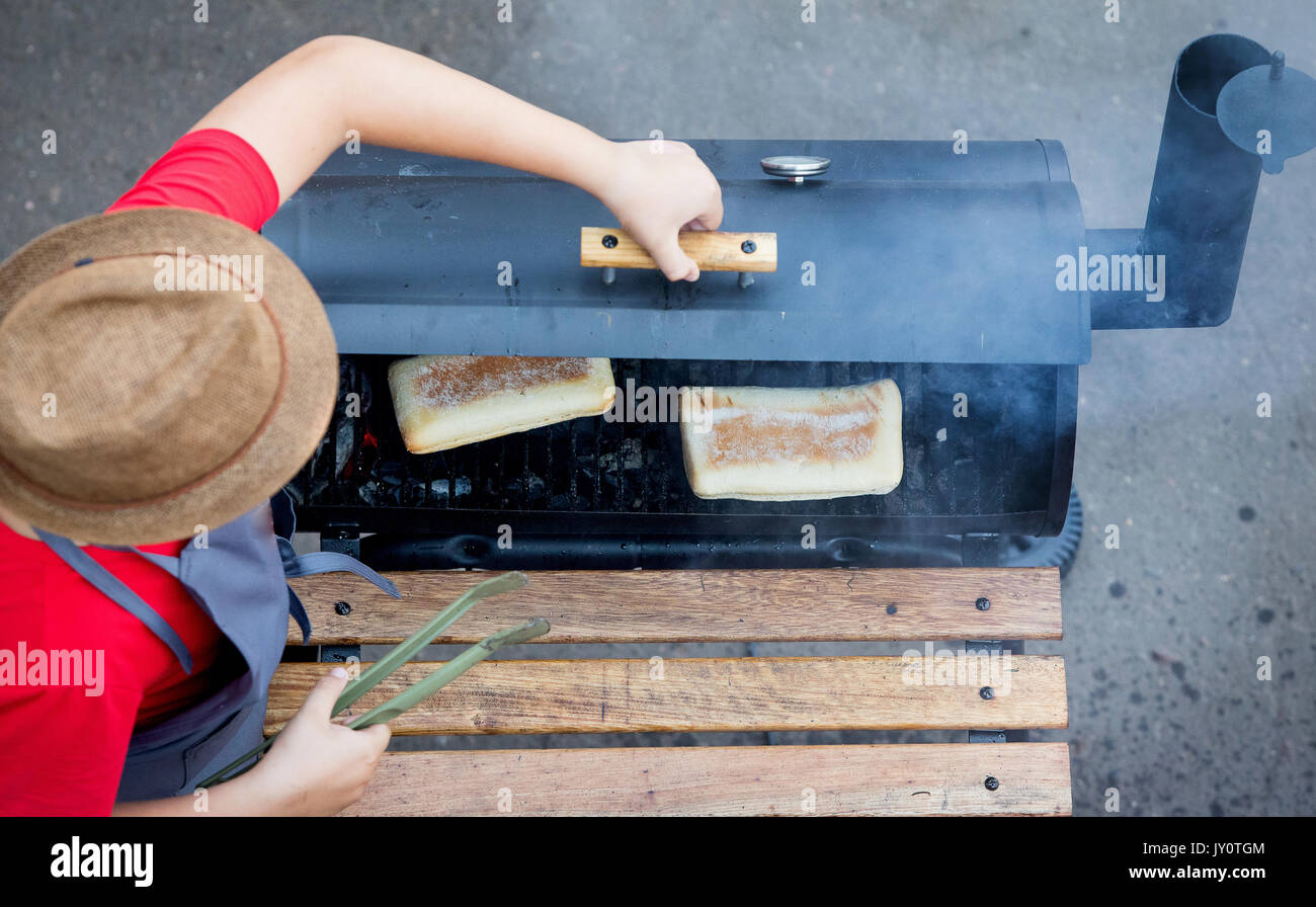 Lo chef nella hat cuoce un Panini nel forno su braci Foto Stock