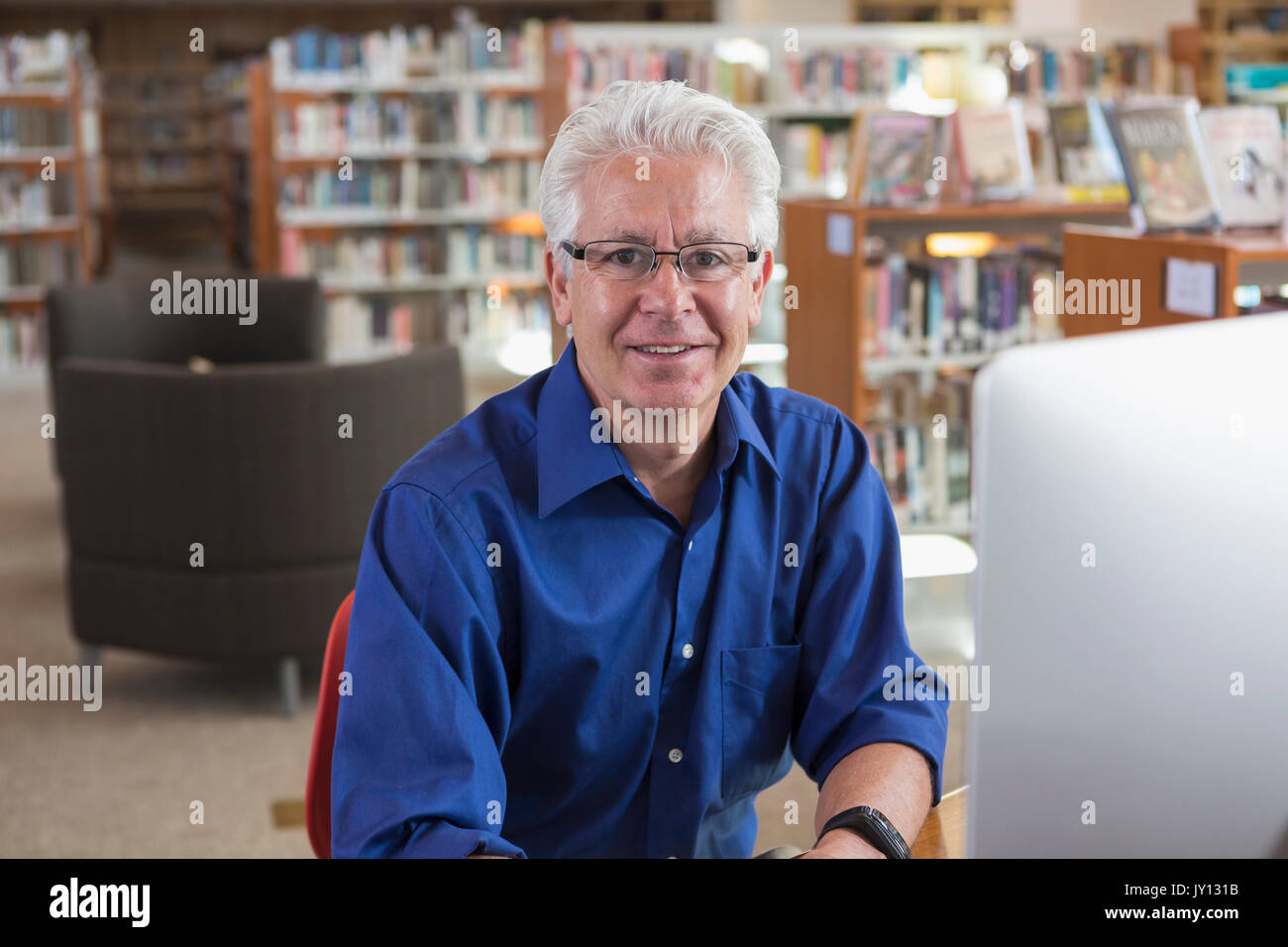 Sorridente uomo ispanico utilizzando computer in biblioteca Foto Stock