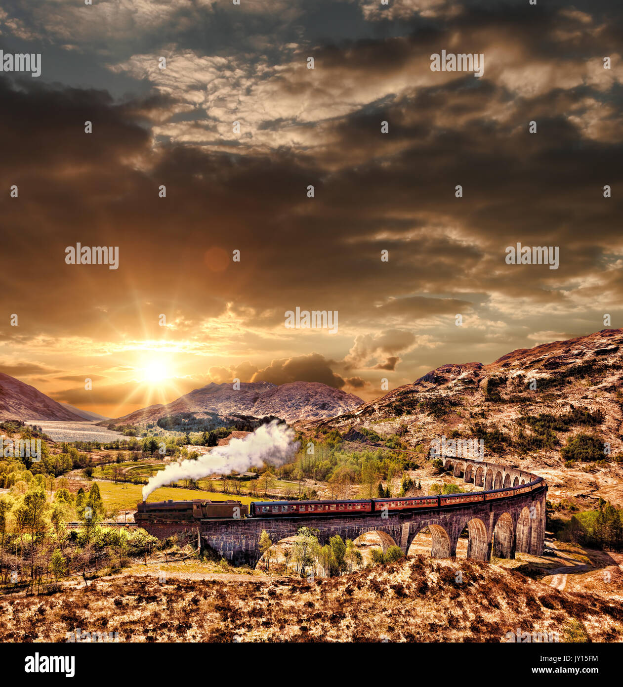Glenfinnan viadotto ferroviario in Scozia con il vapore giacobita treno contro il tramonto sul lago Foto Stock