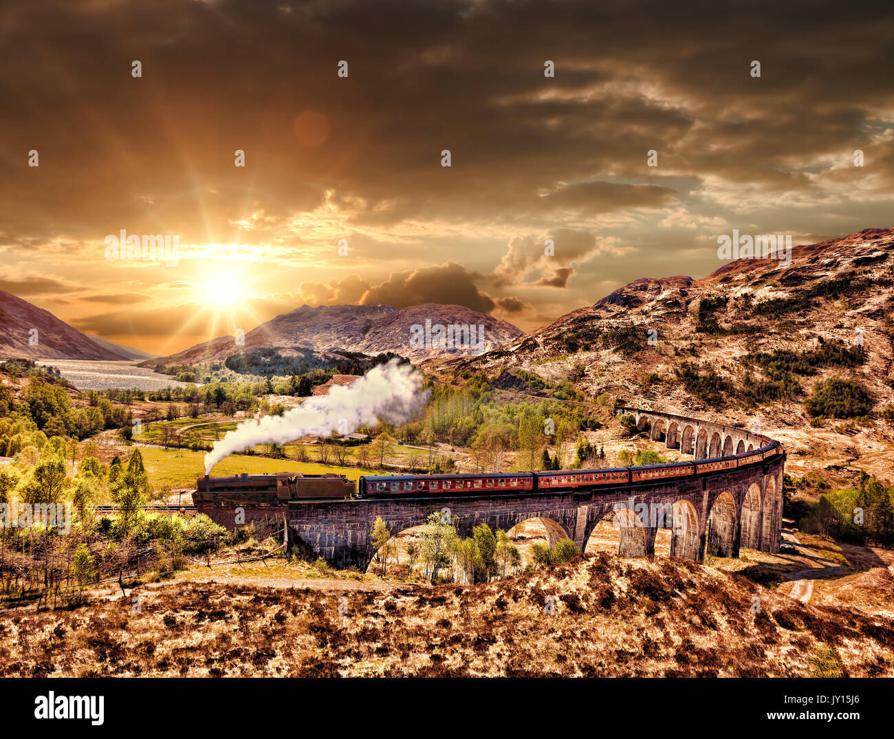 Glenfinnan viadotto ferroviario in Scozia con il vapore giacobita treno contro il tramonto sul lago Foto Stock