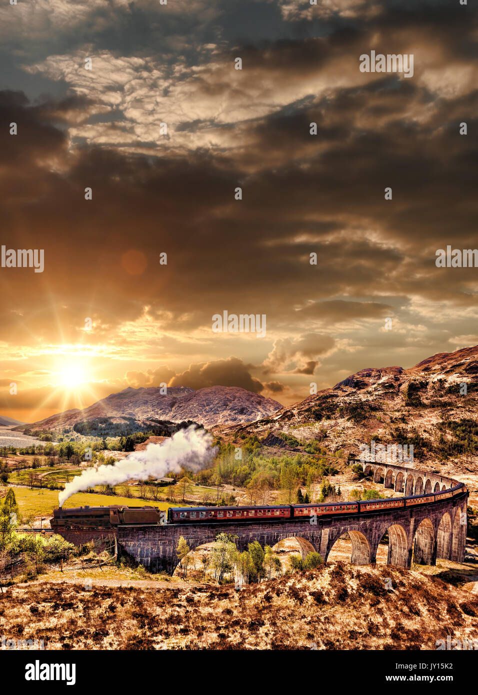 Glenfinnan viadotto ferroviario in Scozia con il vapore giacobita treno contro il tramonto sul lago Foto Stock