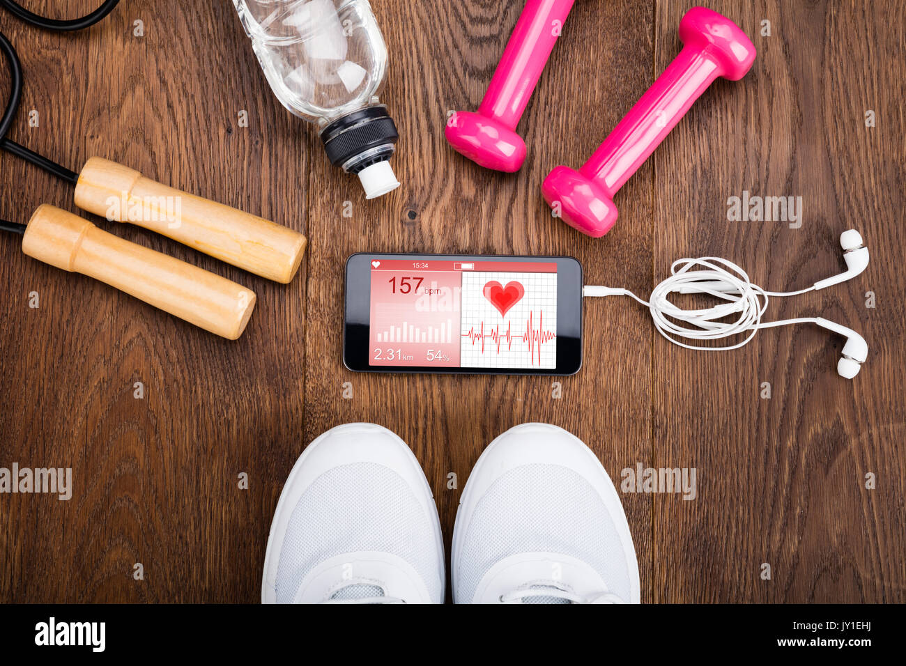 Attrezzatura ginnica con Mobilephone che mostra la salute applicazione su pavimento in legno Foto Stock