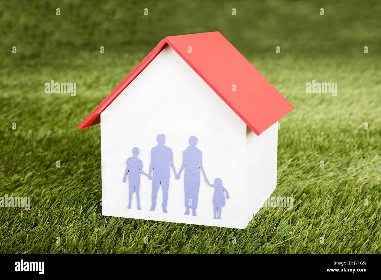 Close-up del modello di casa con la famiglia su di esso sul campo erboso Foto Stock