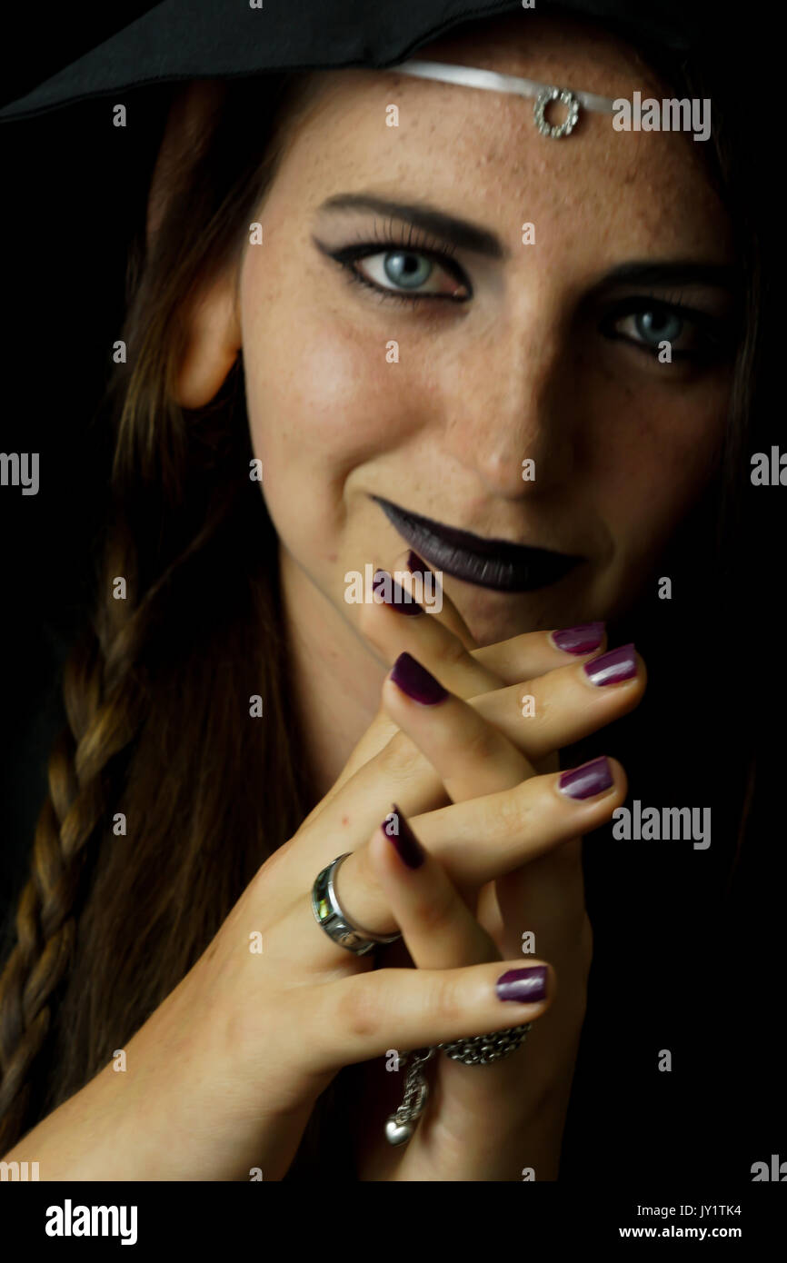 Una giovane donna vestita come un elfo nero con un accappatoio con cappuccio e capelli lunghi con sottolineato elf orecchie Foto Stock