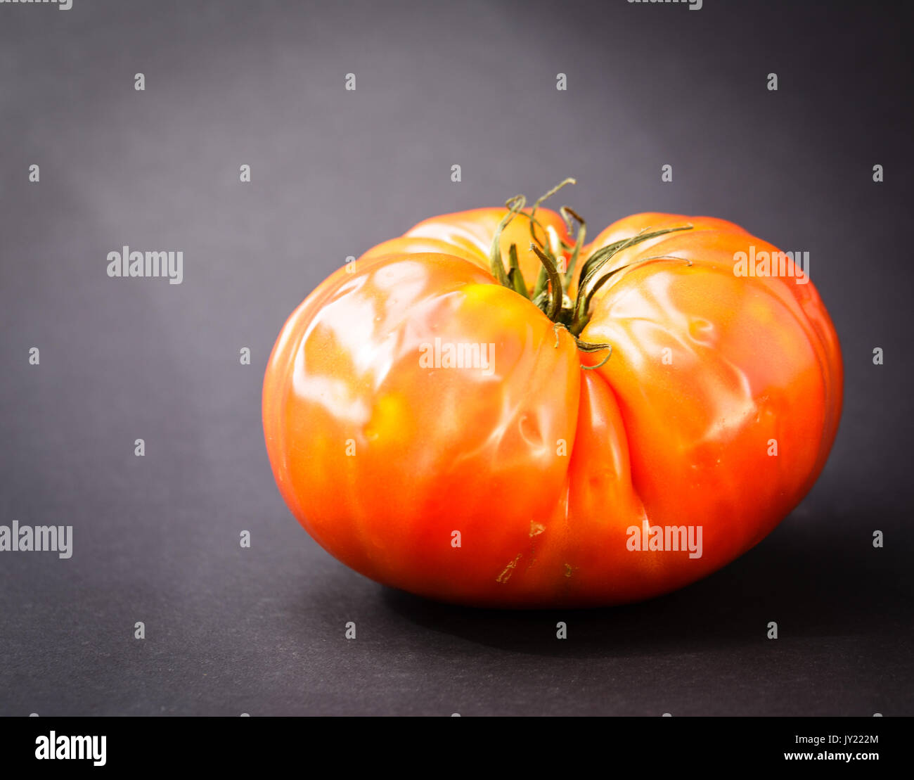 Mature cimelio di pomodoro isolato sul retro nero di massa. Il pomodoro è rosso ed è pronto per essere consumato. Foto Stock