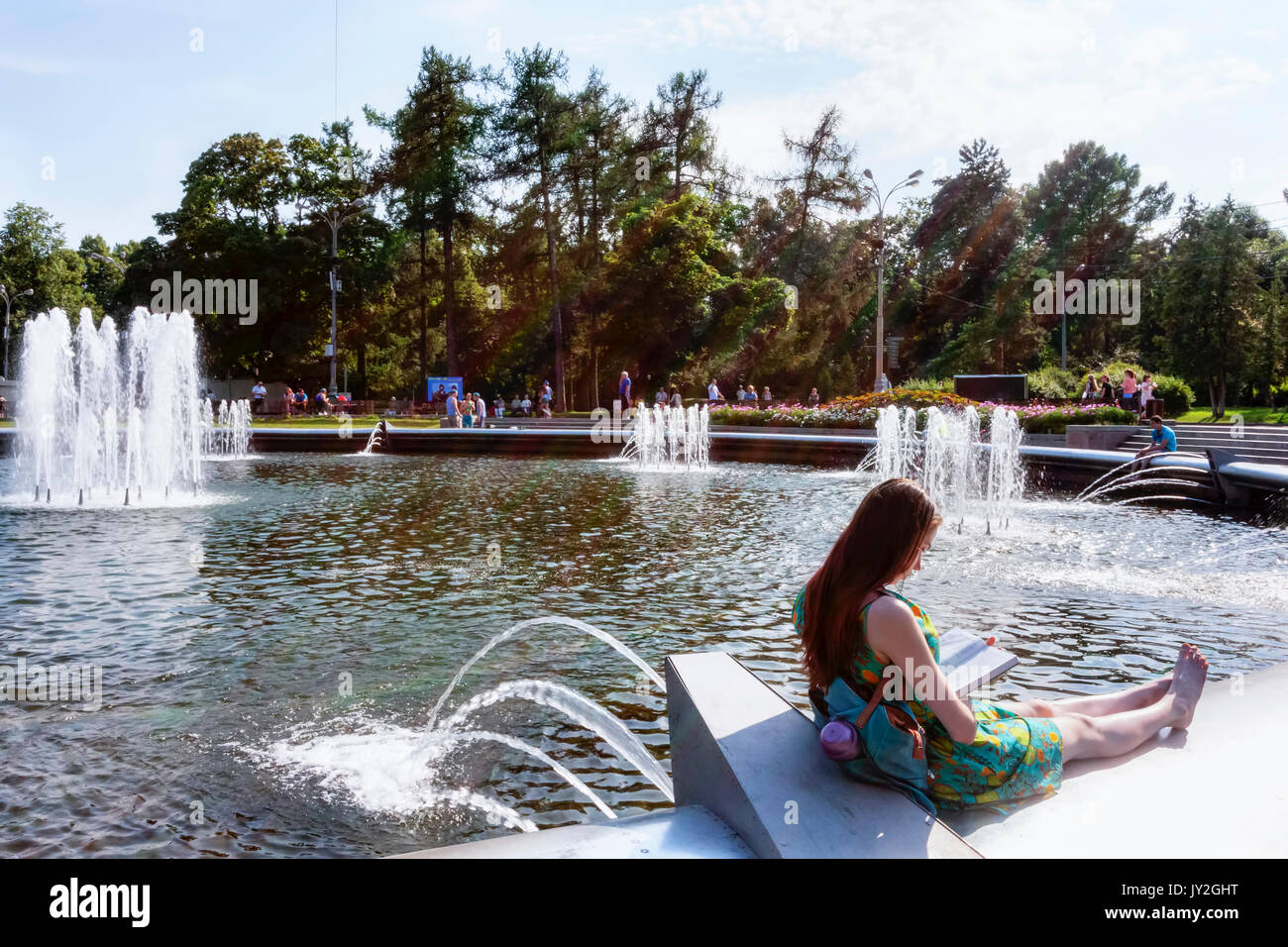 Mosca, Federazione Russa - Agosto 2, 2017: parco Sokolniki donna legge un libro sul bordo della fontana, lei gode del giorno di estate dei marittimi della t Foto Stock