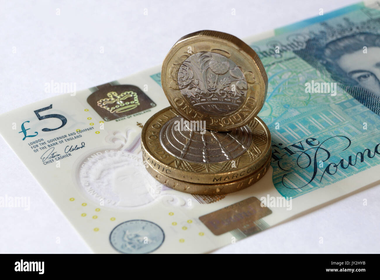 Nuova moneta inglese e nota da cinque sterline Foto Stock