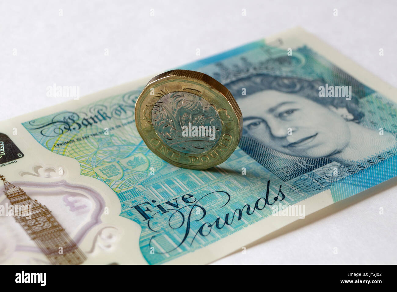 Nuova moneta inglese e nota da cinque sterline Foto Stock