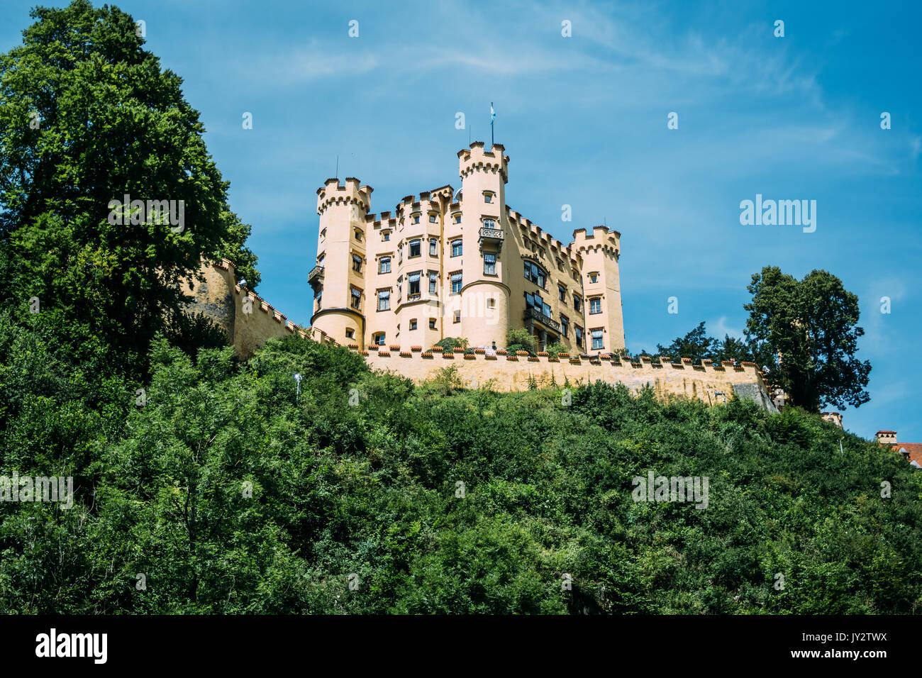 Il castello di Hohenschwangau su una collina con un cielo blu visto dal di sotto. Foto Stock