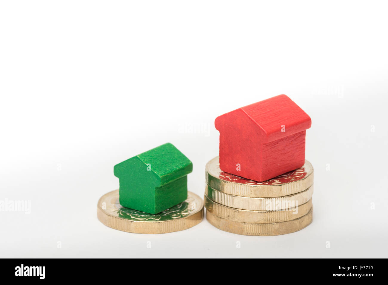 Mercato immobiliare. Sterlina britannica monete isolato su sfondo bianco con rosso e verde giocattolo di legno case. Simboli di mutui, prestiti, debiti e ipoteche Foto Stock