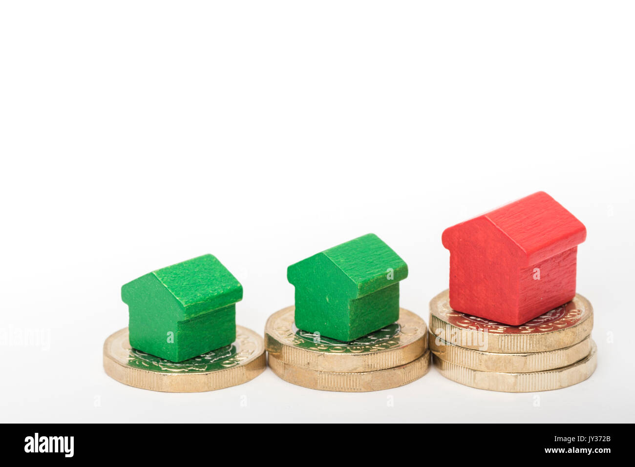 Mercato immobiliare. Sterlina britannica monete isolato su sfondo bianco con rosso e verde giocattolo di legno case. Simboli di mutui, prestiti, debiti e ipoteche Foto Stock