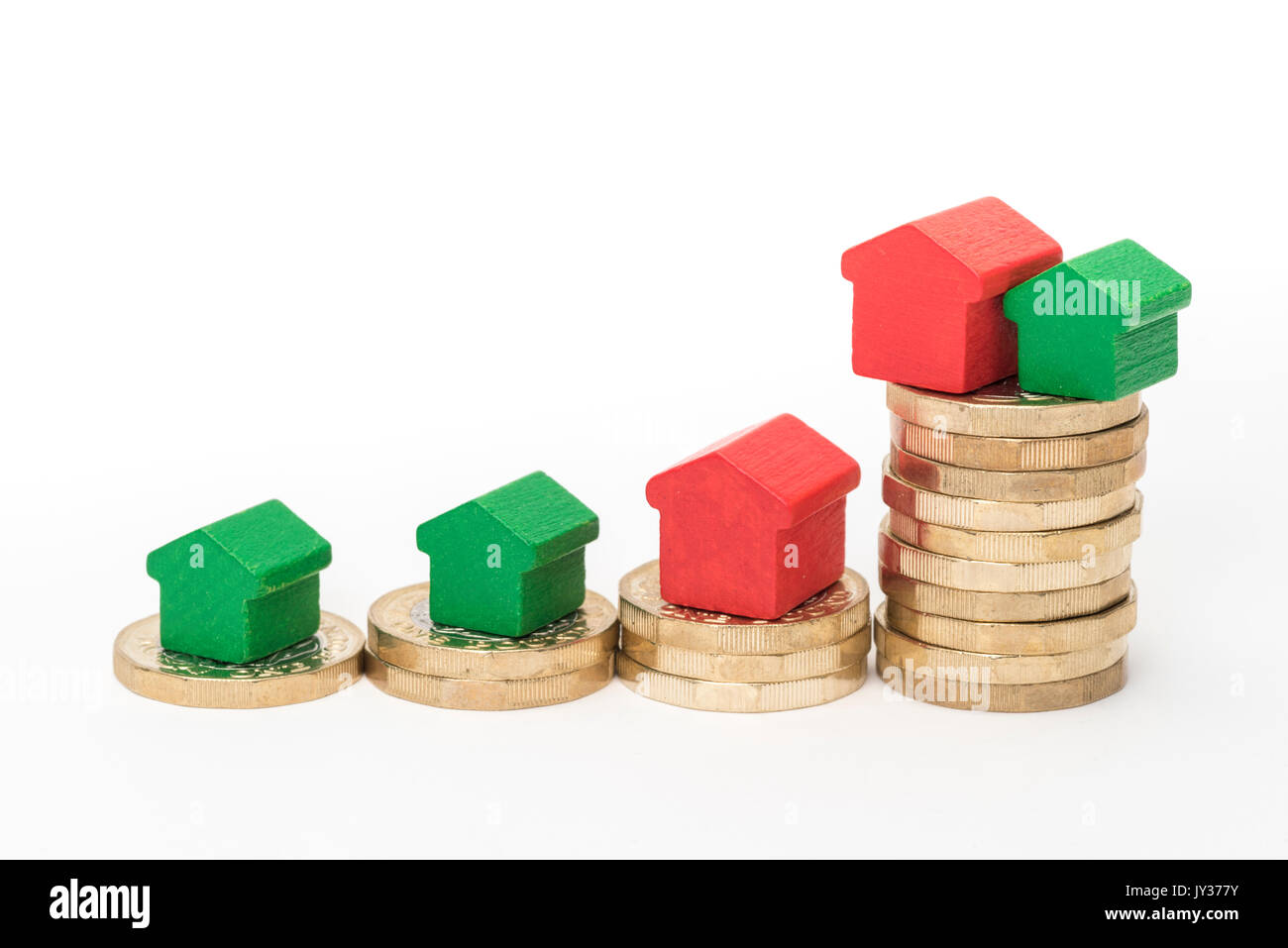 Mercato immobiliare. Sterlina britannica monete isolato su sfondo bianco con rosso e verde giocattolo di legno case. Simboli di mutui, prestiti, debiti e ipoteche Foto Stock