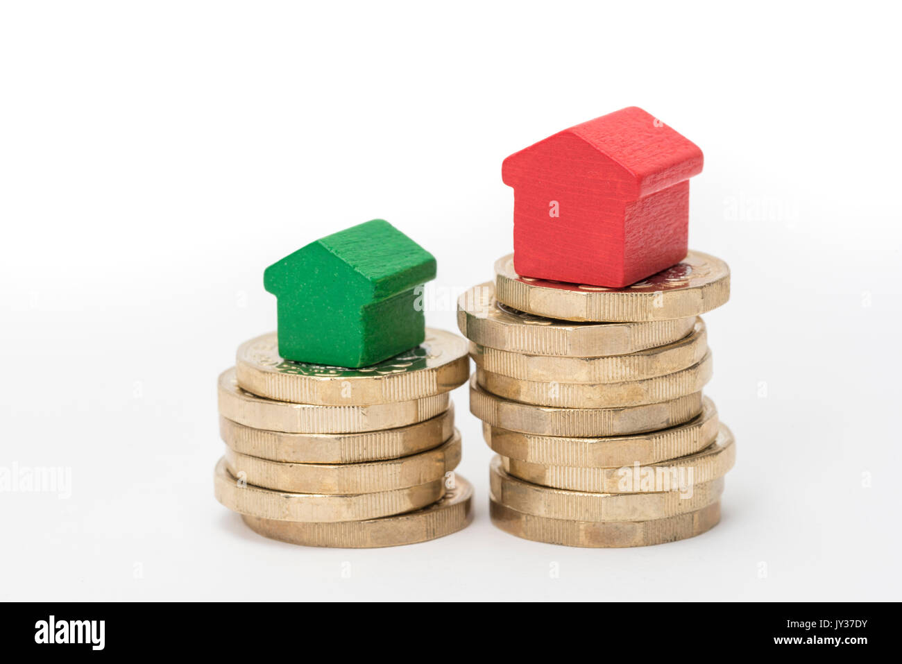 Mercato immobiliare. Sterlina britannica monete isolato su sfondo bianco con rosso e verde giocattolo di legno case. Simboli di mutui, prestiti, debiti e ipoteche Foto Stock