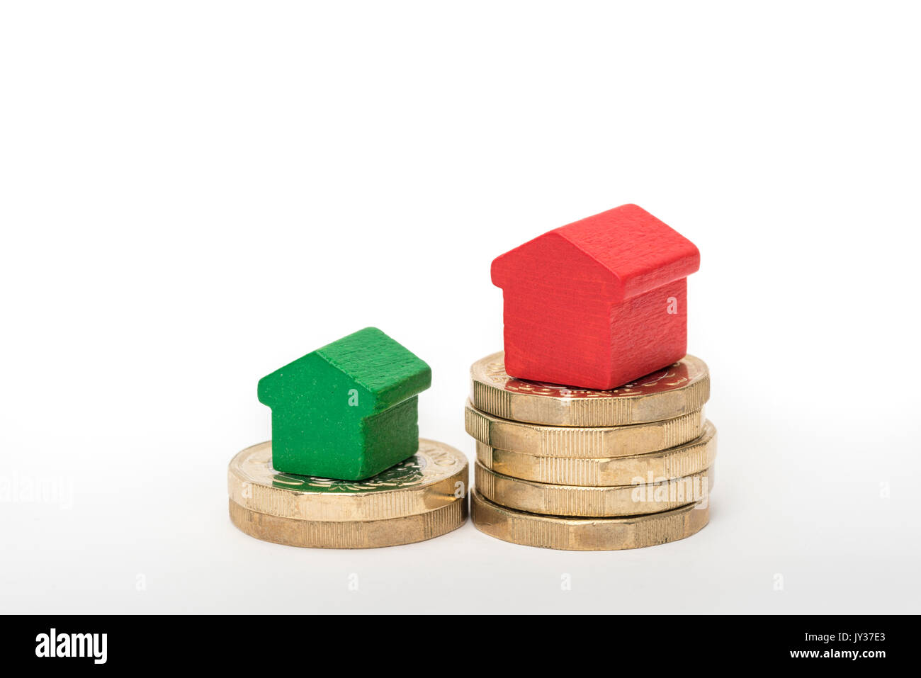 Mercato immobiliare. Sterlina britannica monete isolato su sfondo bianco con rosso e verde giocattolo di legno case. Simboli di mutui, prestiti, debiti e ipoteche Foto Stock