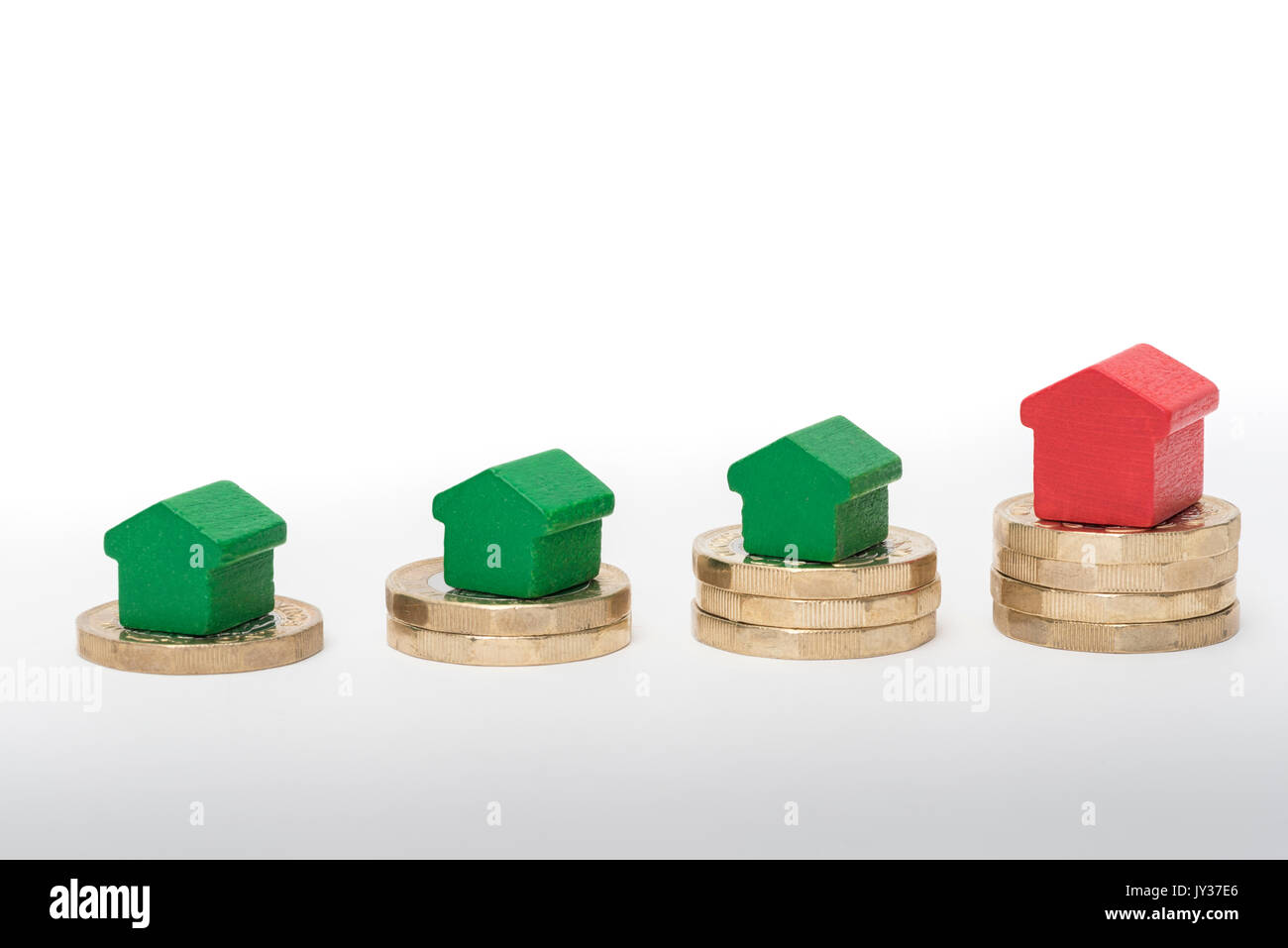 Mercato immobiliare. Sterlina britannica monete isolato su sfondo bianco con rosso e verde giocattolo di legno case. Simboli di mutui, prestiti, debiti e ipoteche Foto Stock