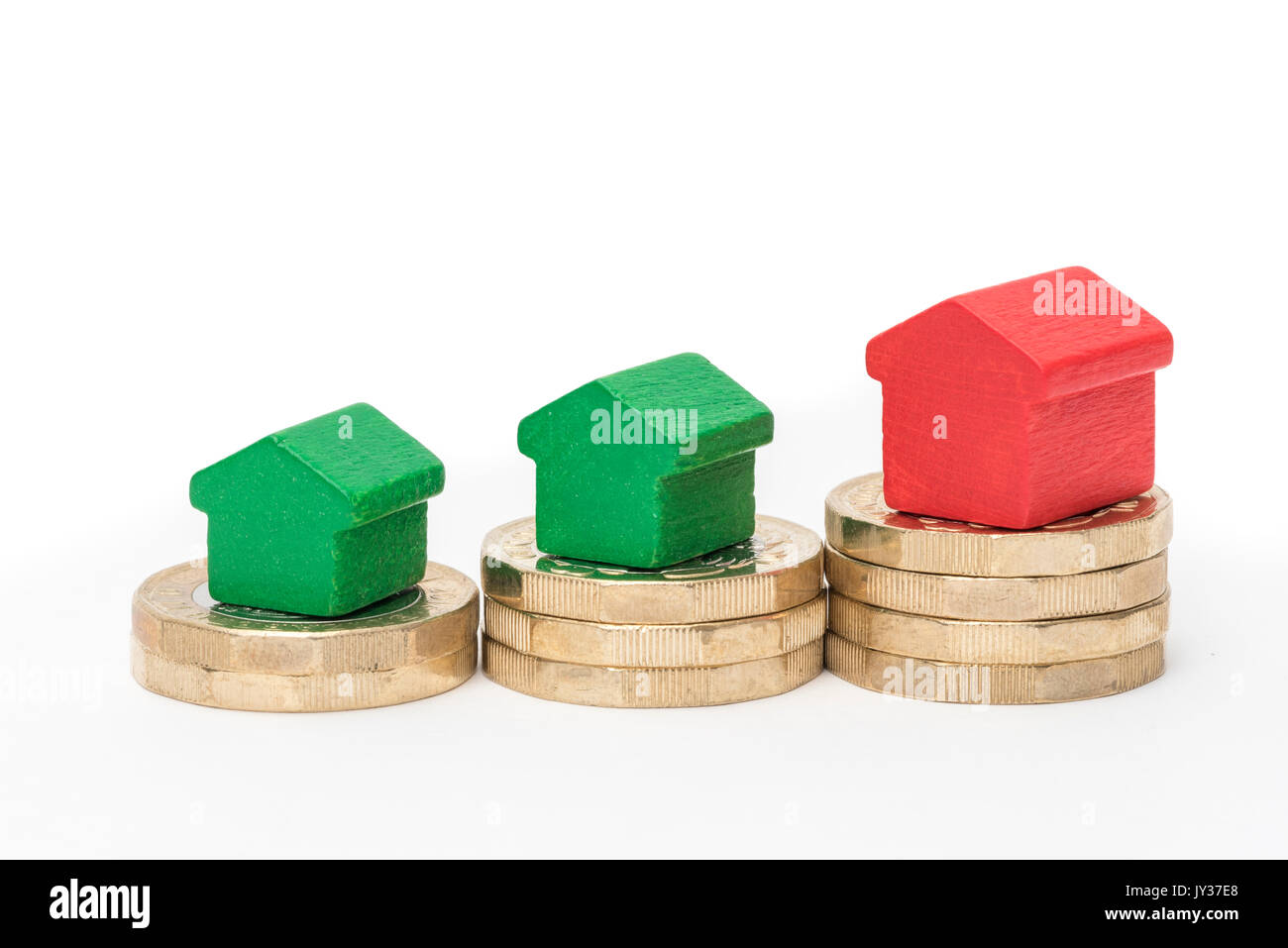 Mercato immobiliare. Sterlina britannica monete isolato su sfondo bianco con rosso e verde giocattolo di legno case. Simboli di mutui, prestiti, debiti e ipoteche Foto Stock