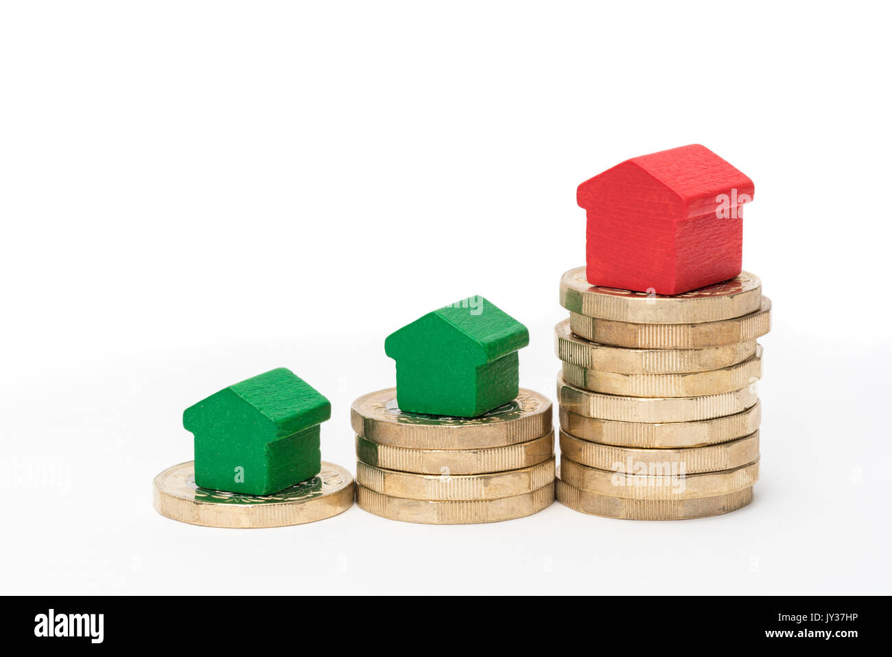 Mercato immobiliare. Sterlina britannica monete isolato su sfondo bianco con rosso e verde giocattolo di legno case. Simboli di mutui, prestiti, debiti e ipoteche Foto Stock