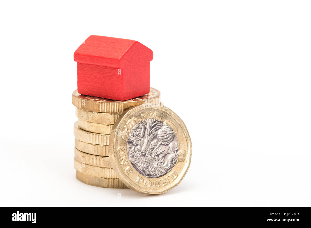 Mercato immobiliare. Sterlina britannica monete isolato su sfondo bianco con rosso e verde giocattolo di legno case. Simboli di mutui, prestiti, debiti e ipoteche Foto Stock