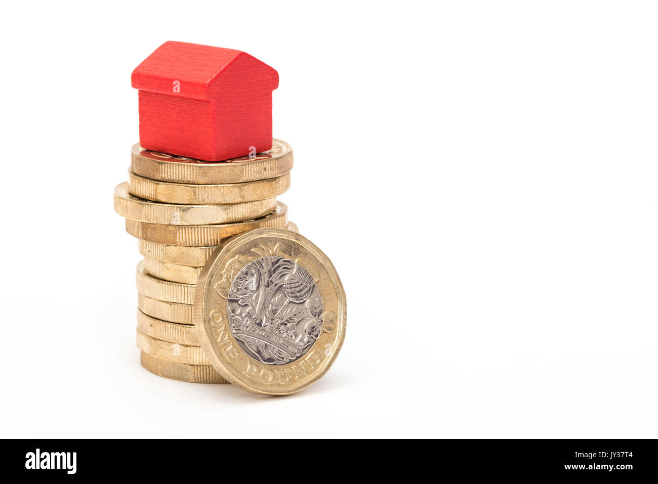 Mercato immobiliare. Sterlina britannica monete isolato su sfondo bianco con rosso e verde giocattolo di legno case. Simboli di mutui, prestiti, debiti e ipoteche Foto Stock