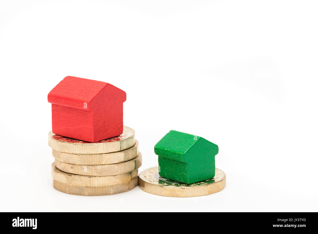 Mercato immobiliare. Sterlina britannica monete isolato su sfondo bianco con rosso e verde giocattolo di legno case. Simboli di mutui, prestiti, debiti e ipoteche Foto Stock