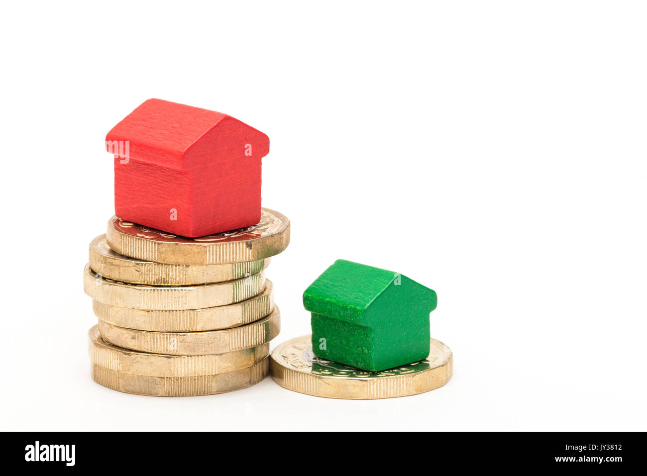 Mercato immobiliare. Sterlina britannica monete isolato su sfondo bianco con rosso e verde giocattolo di legno case. Simboli di mutui, prestiti, debiti e ipoteche Foto Stock