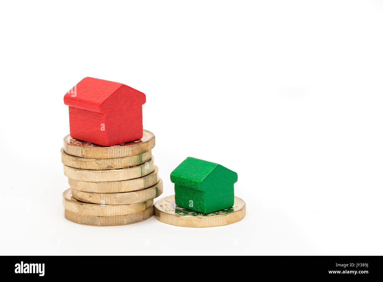 Mercato immobiliare. Sterlina britannica monete isolato su sfondo bianco con rosso e verde giocattolo di legno case. Simboli di mutui, prestiti, debiti e ipoteche Foto Stock
