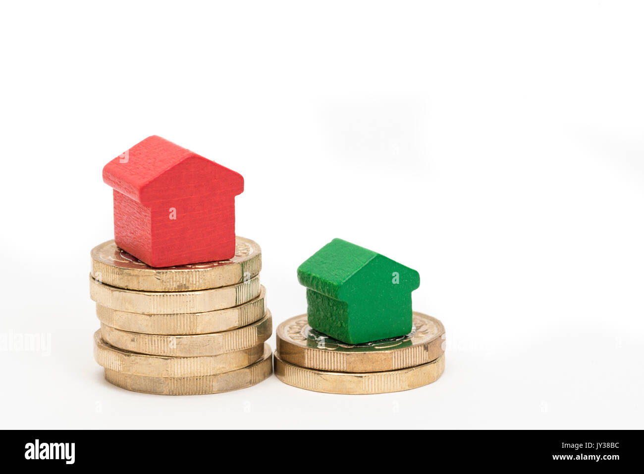 Mercato immobiliare. Sterlina britannica monete isolato su sfondo bianco con rosso e verde giocattolo di legno case. Simboli di mutui, prestiti, debiti e ipoteche Foto Stock