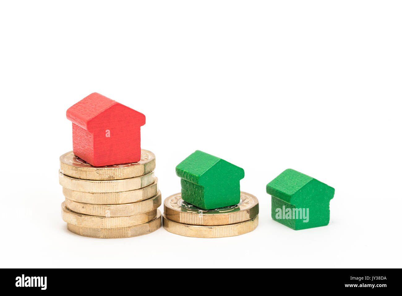 Mercato immobiliare. Sterlina britannica monete isolato su sfondo bianco con rosso e verde giocattolo di legno case. Simboli di mutui, prestiti, debiti e ipoteche Foto Stock