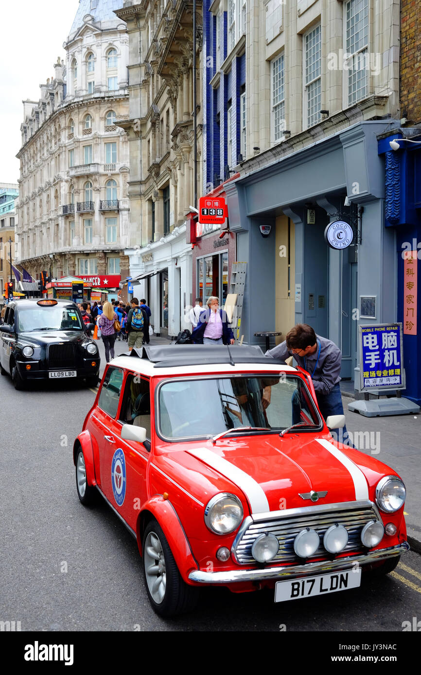 Un classico mini auto con uno di Londra i famosi taxi neri dietro di esso, in Wardour Street, Soho vicino a Chinatown, Londra Foto Stock