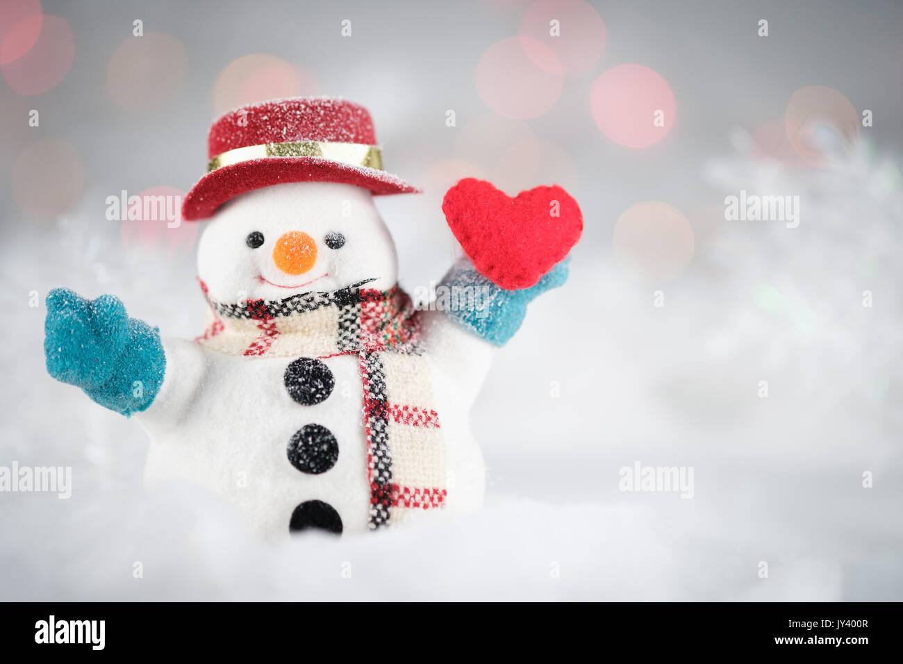 Un pupazzo di neve e mini cuore cuscino sul bokeh sfondo, con copia spazio per il messaggio di saluto di stagione. Auguri di Buon Natale o felice anno nuovo, la selezione del punto AF, classe Foto Stock