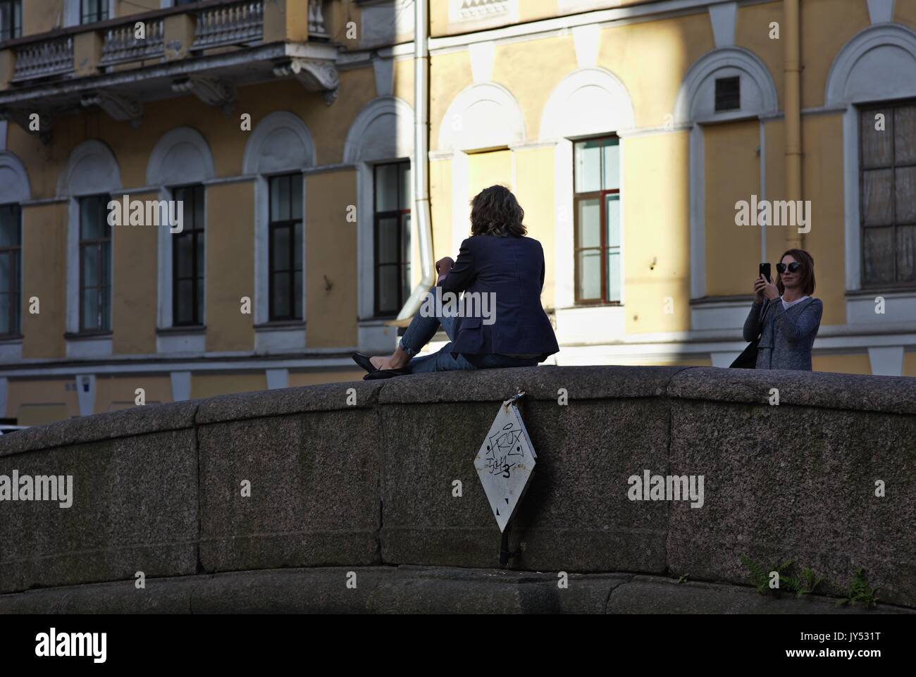 La donna posa per telefono cellulare foto sulla balaustra del ponte Foto Stock