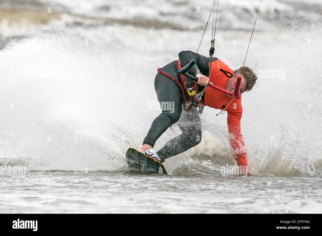 Southport, Merseyside, 19 agosto 2017. Regno Unito Meteo. Davvero un ventoso e molto più freddo giorno con alcuni pesanti Scattered Showers non scoraggiare questo kite boarder da equitazione il surf sulla marea a Southport nel Merseyside. Credito: Cernan Elias/Alamy Live News Foto Stock