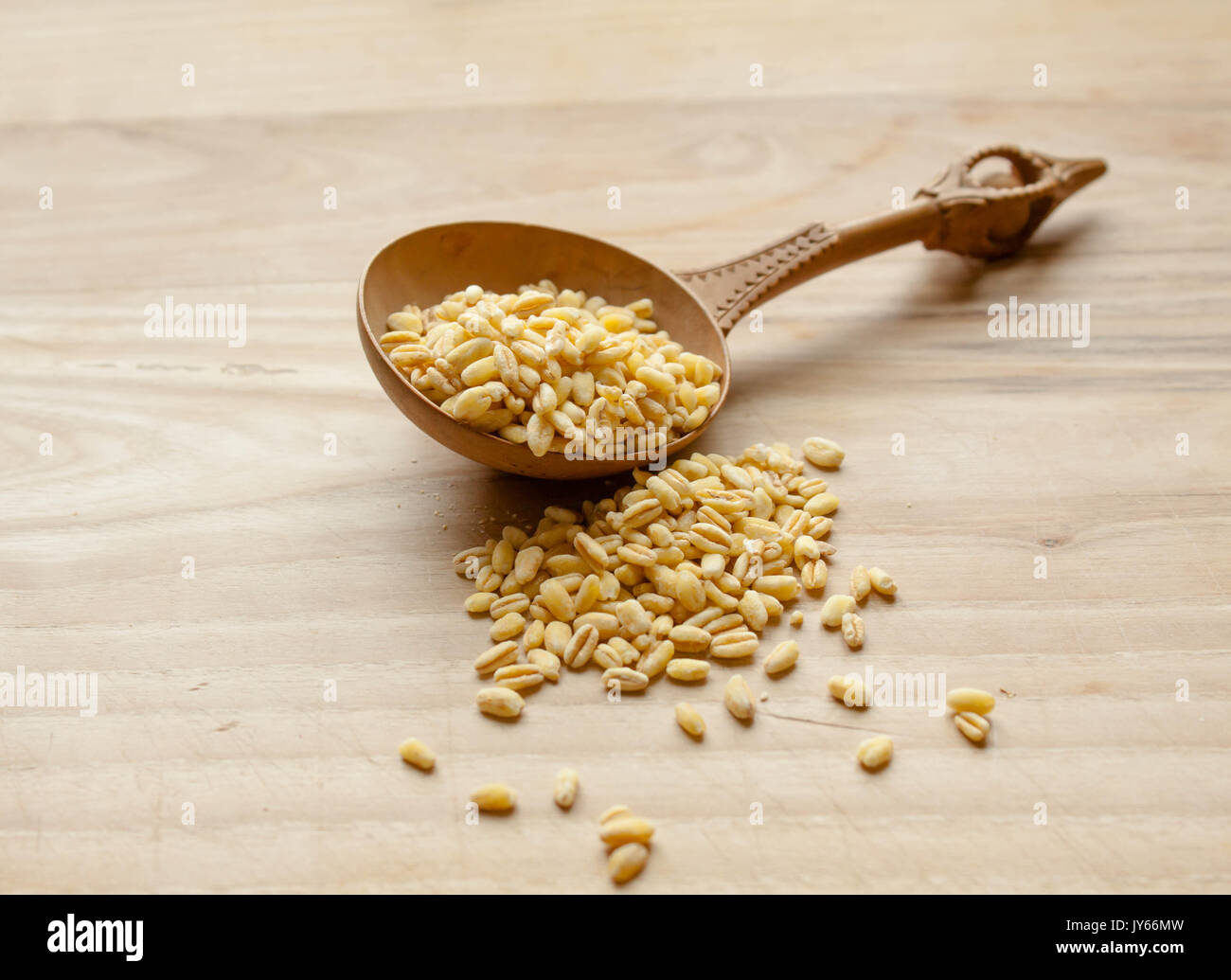 Vecchio cucchiaio di legno isolata con grani di grano sul tavolo di legno in cucina Foto Stock