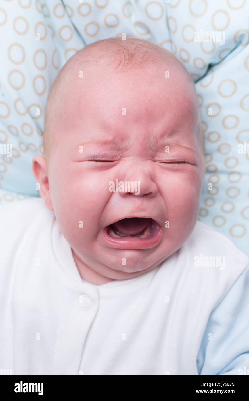 Ritratto di un simpatico bimbo seduto e pianto. Adorabili sette mesi del bambino. Foto Stock
