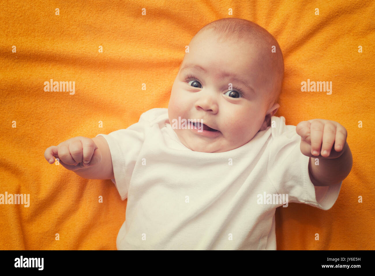 Ritratto di un simpatico bimbo giacente su arancione coperta. Adorabili e sette mesi di età bambino felice. Foto Stock