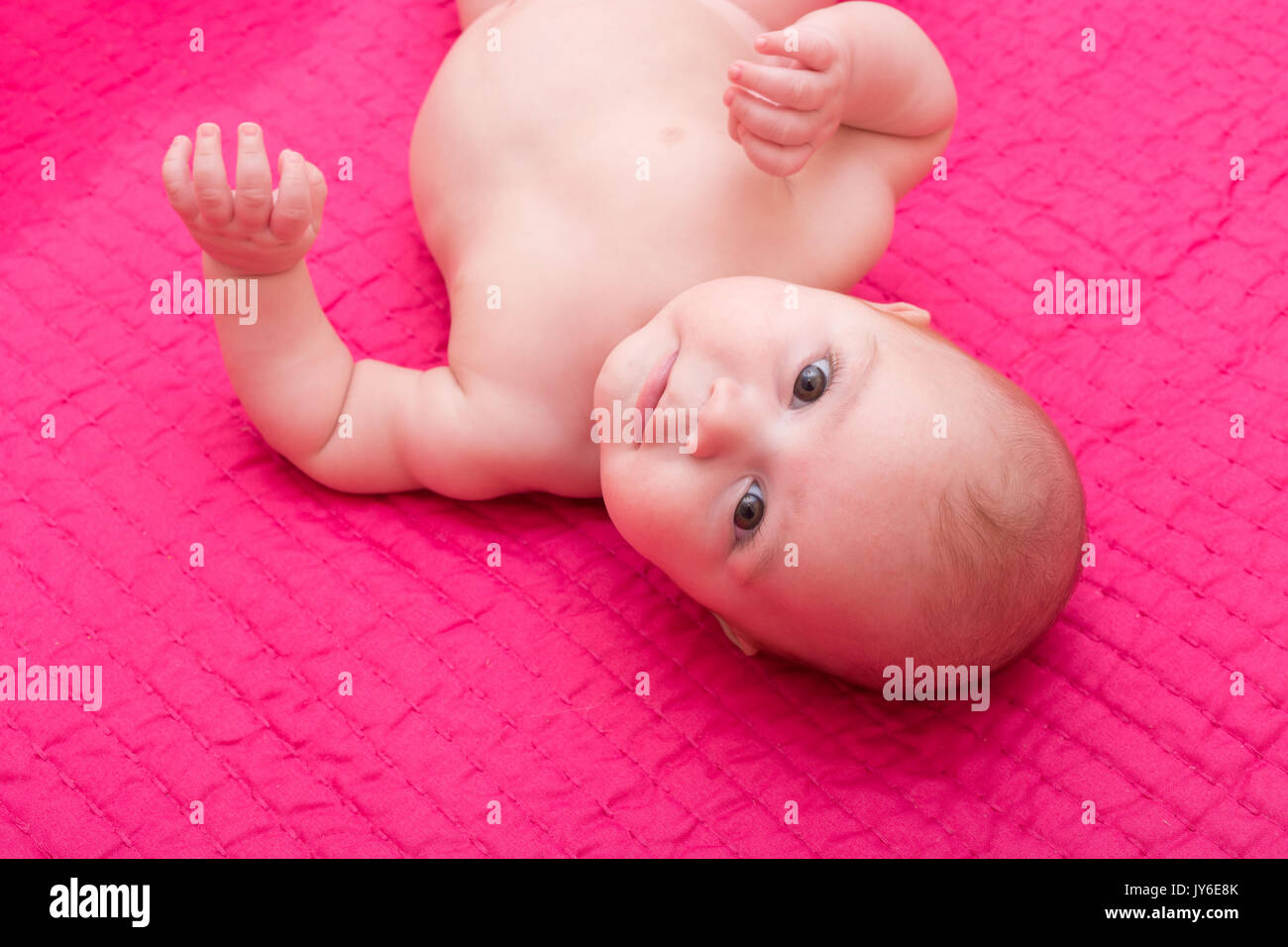 Ritratto di un simpatico bimbo giacente sulla coperta di fucsia. Adorabili e sette mesi di età bambino felice. Foto Stock