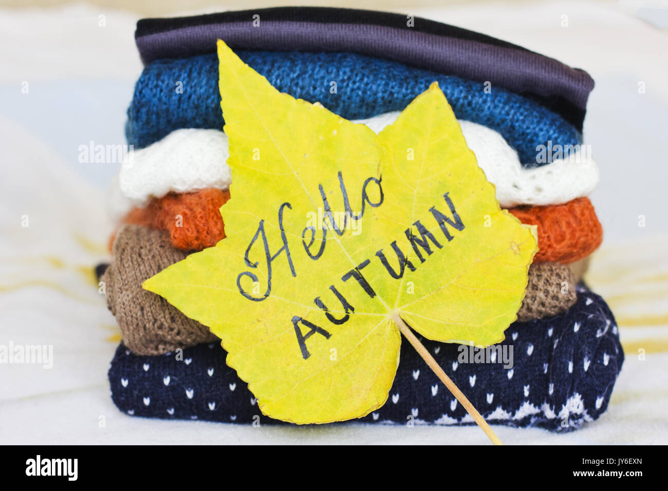 Una pila di maglioni caldi e un giallo maple leaf Foto Stock