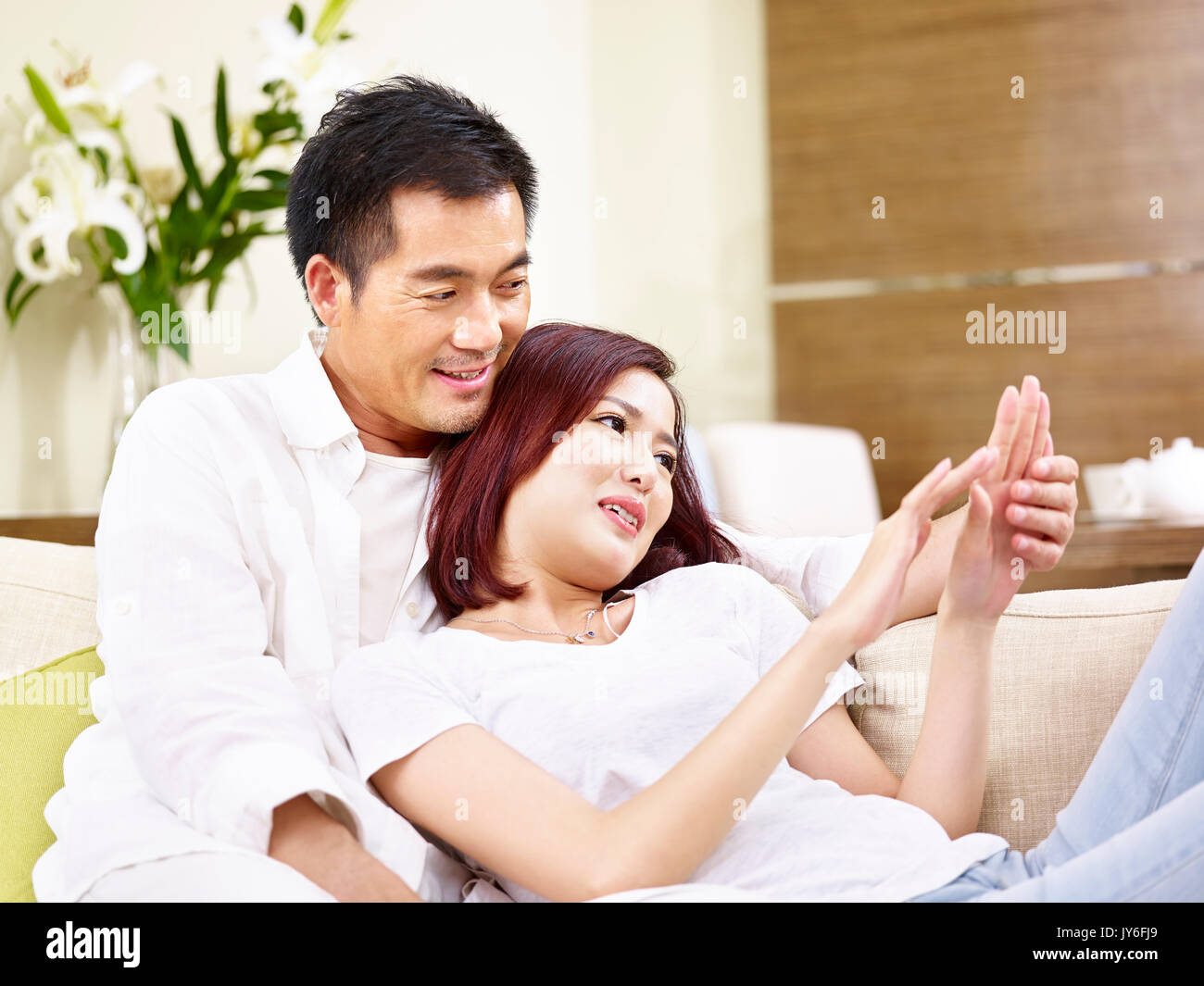 Giovani asiatici giovane seduto sul divano e chat a casa Foto Stock