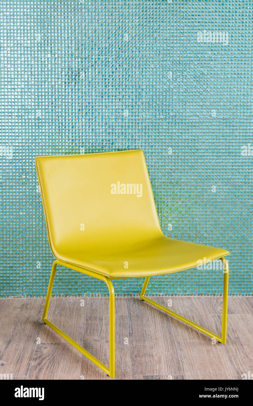 Vuoto sedia giallo su blu parete piastrelle Foto Stock