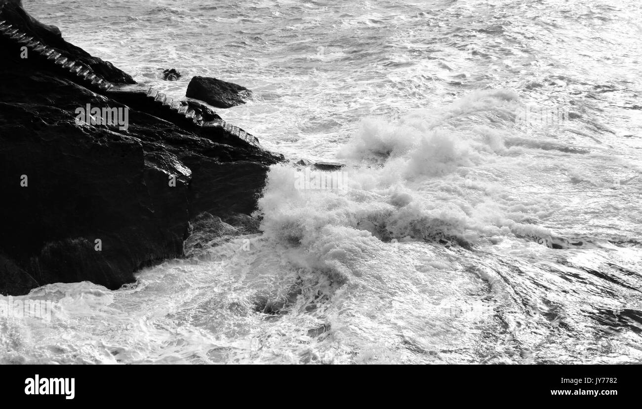 Bianco e nero mare drammatico, scale nella roccia e tempestoso acqua Foto Stock