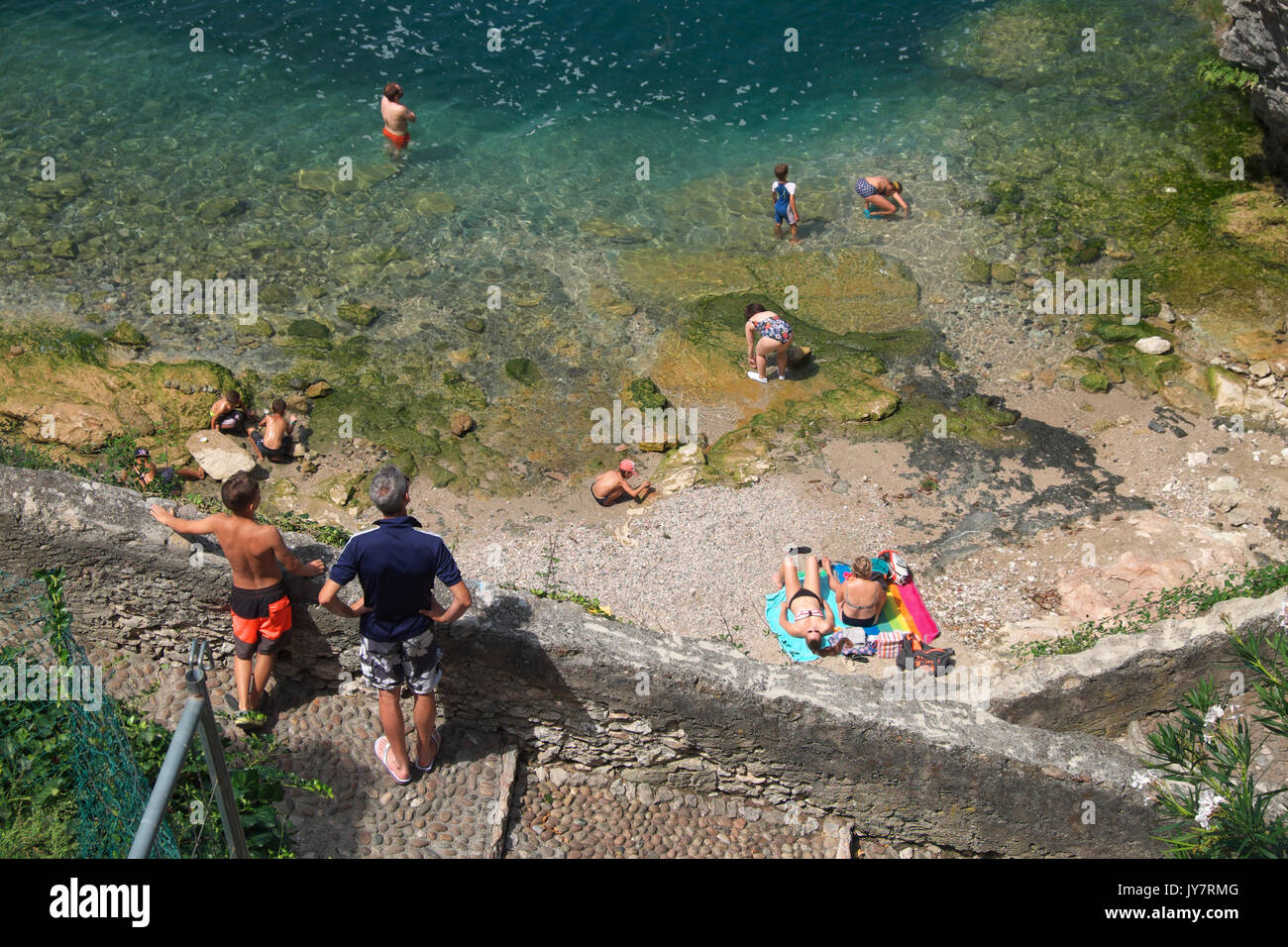 Malcesine, Lago di Garda, Italia - i turisti nuotare nel lago di Garda ad una piccola spiaggia di Malcesine Foto Stock