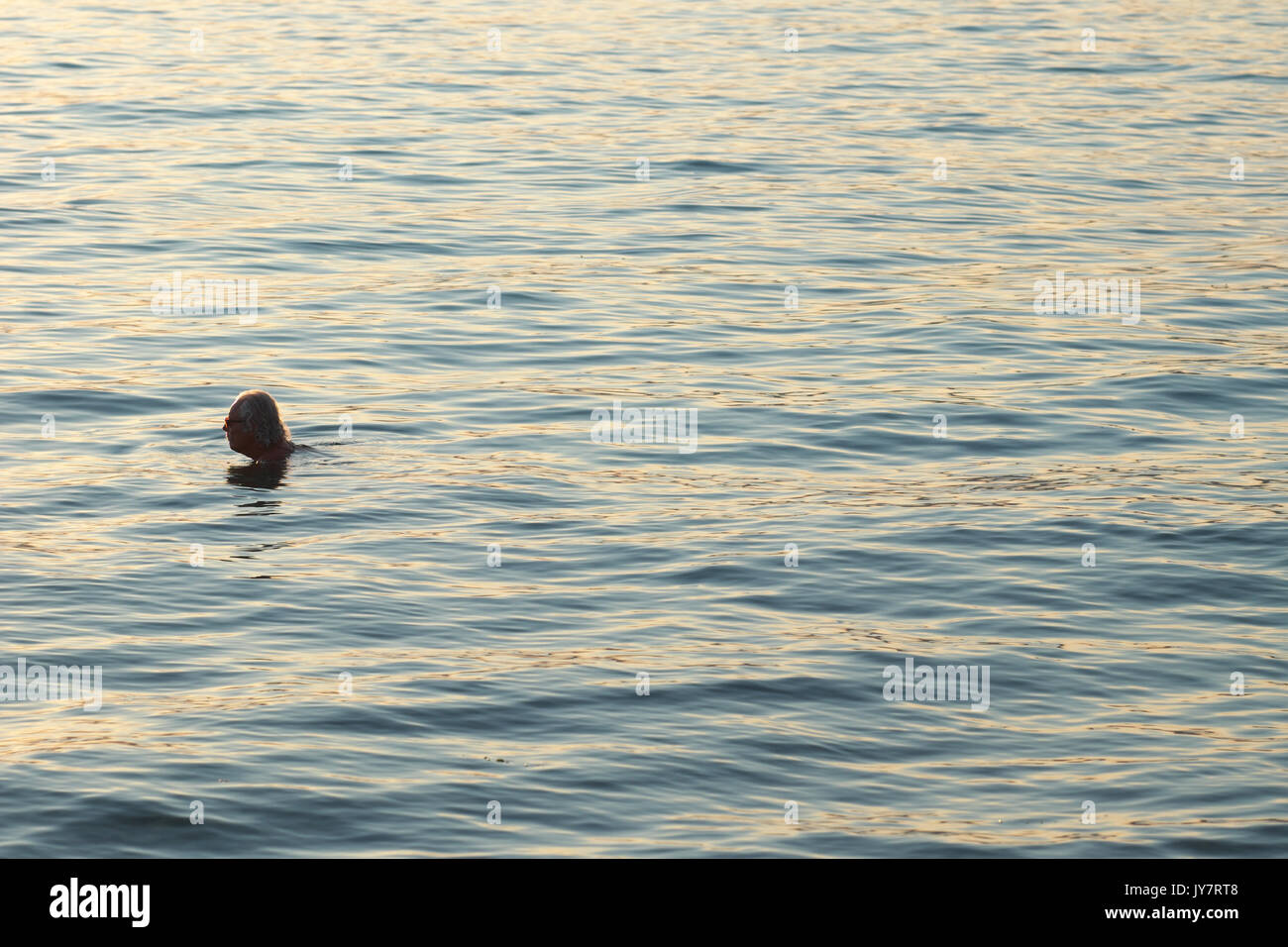Il lago di Garda, Italia uomo anziano nuotare nel lago di Garda in sera twlight Foto Stock