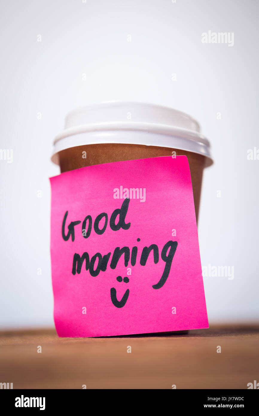 Il livello superficiale di buon mattino il testo incollato sulla tazza monouso contro la parete Foto Stock