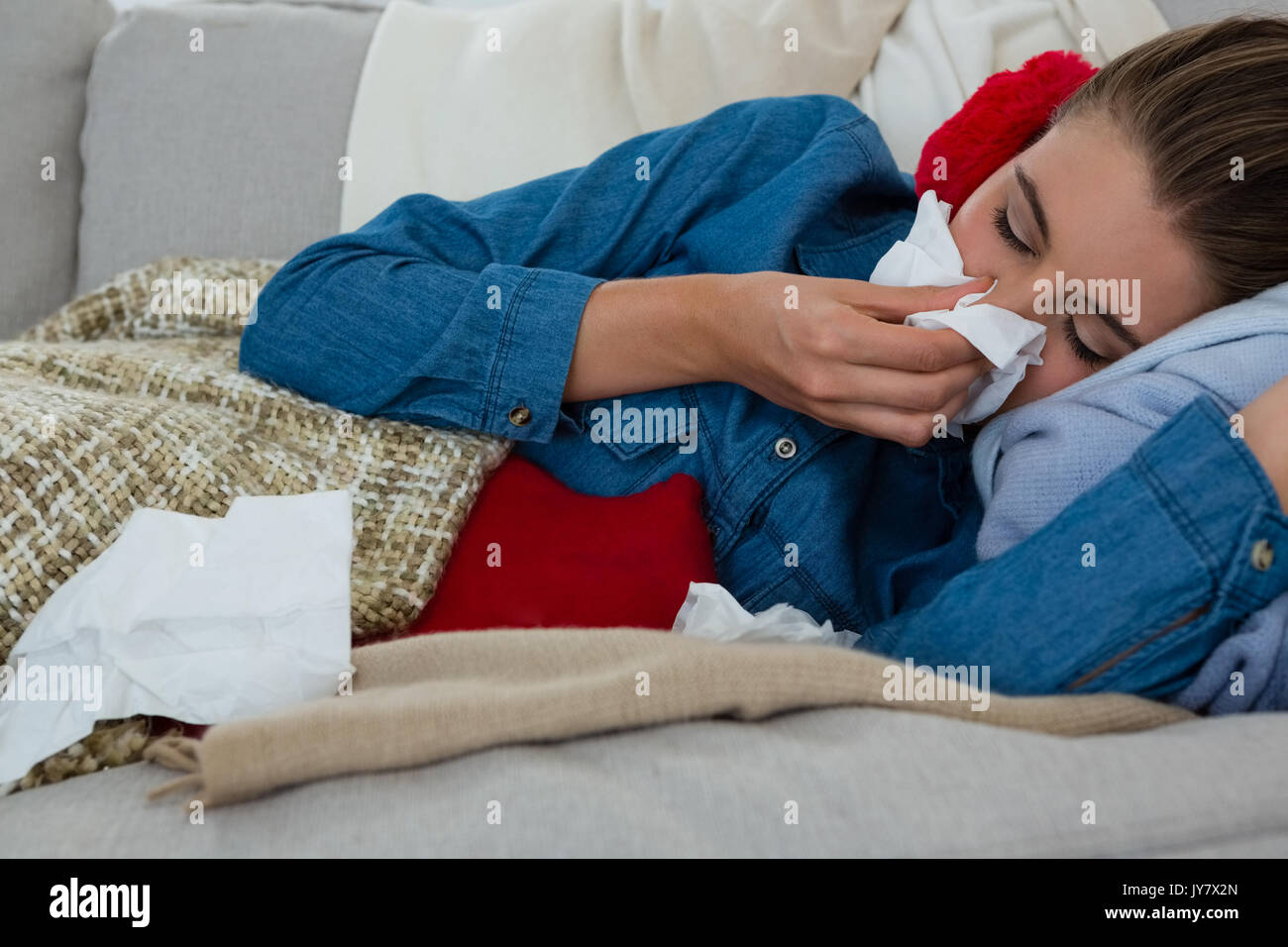 Donna Rosa di sfregamento con il tessuto mentre sdraiato sul divano di casa Foto Stock